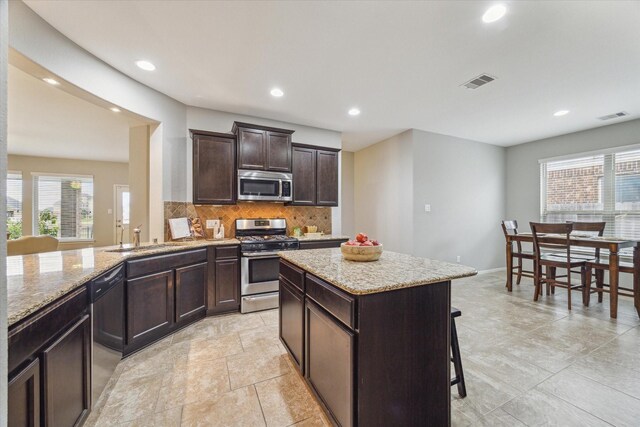 kitchen featuring decorative backsplash, appliances with stainless steel finishes, sink, a center island, and a breakfast bar area