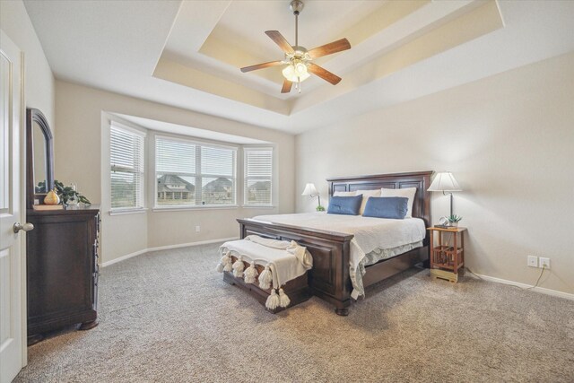 bedroom featuring a raised ceiling, ceiling fan, and carpet flooring