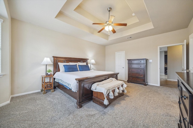 bedroom with light colored carpet, a raised ceiling, and ceiling fan