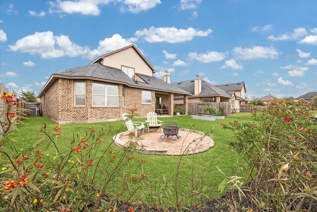 rear view of house with a fire pit, a patio area, and a yard