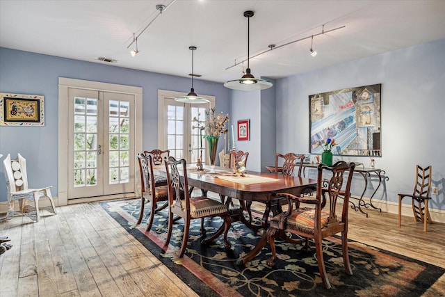 dining area featuring french doors, track lighting, and hardwood / wood-style floors