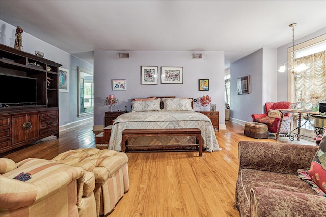 bedroom with a notable chandelier, wood-type flooring, and multiple windows