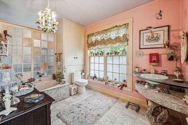 bathroom with a washtub, toilet, sink, and an inviting chandelier