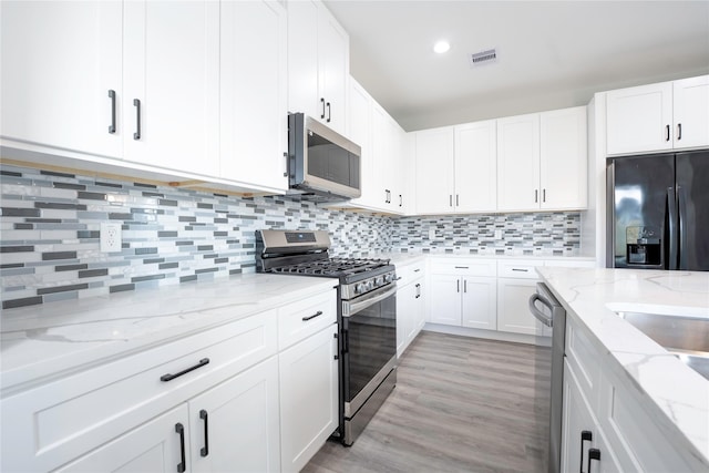 kitchen featuring decorative backsplash, light stone countertops, white cabinetry, and stainless steel appliances