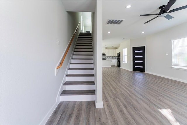 stairs featuring hardwood / wood-style floors, ceiling fan, and plenty of natural light