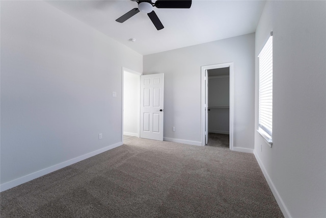 unfurnished bedroom with ceiling fan, a walk in closet, carpet floors, and a closet