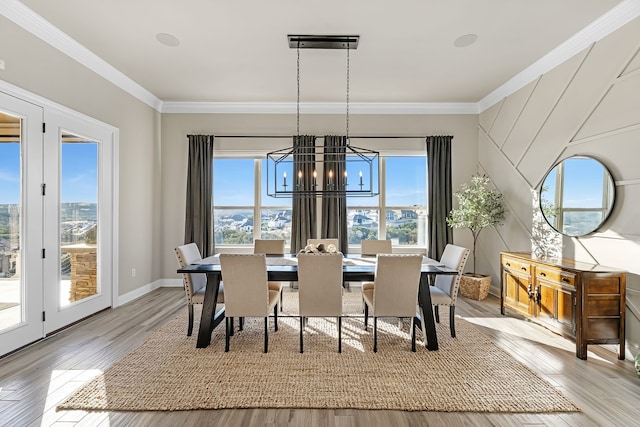 dining area with ornamental molding, light hardwood / wood-style floors, and a notable chandelier