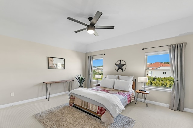 bedroom featuring ceiling fan, light colored carpet, and multiple windows