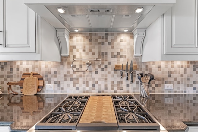 kitchen featuring tasteful backsplash, island range hood, white cabinets, and stainless steel gas stovetop