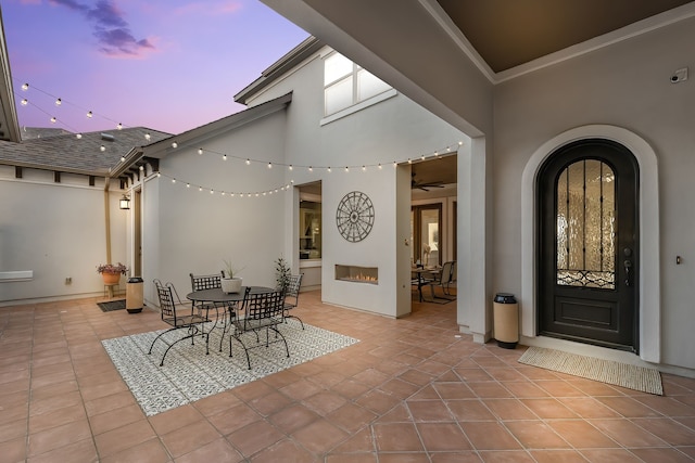 patio terrace at dusk with a warm lit fireplace and outdoor dining space