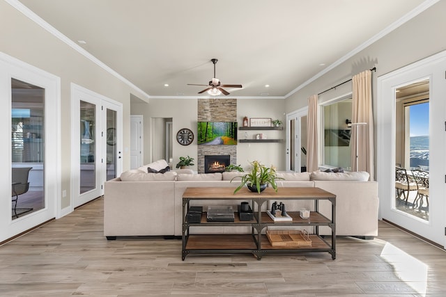 living room with crown molding, light hardwood / wood-style flooring, ceiling fan, a fireplace, and french doors