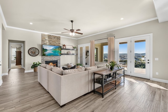 living room featuring light wood-style flooring, ornamental molding, and a stone fireplace