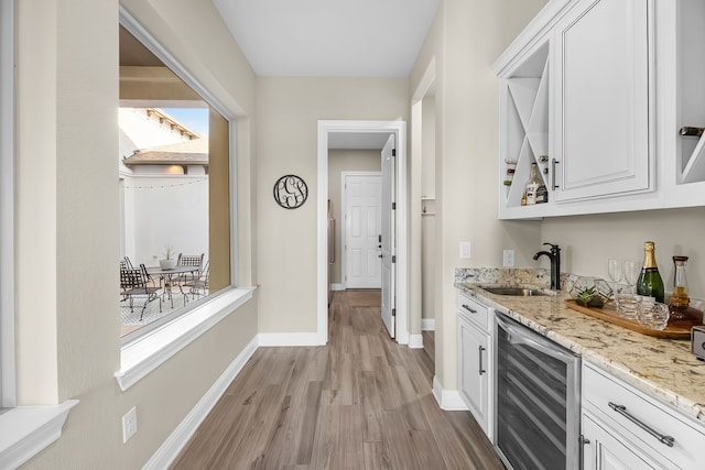 bar featuring white cabinetry, sink, and beverage cooler