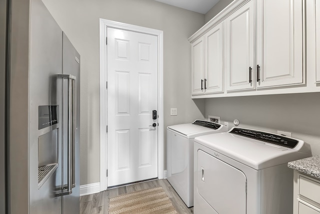 washroom with cabinet space, washing machine and dryer, and light wood-style floors