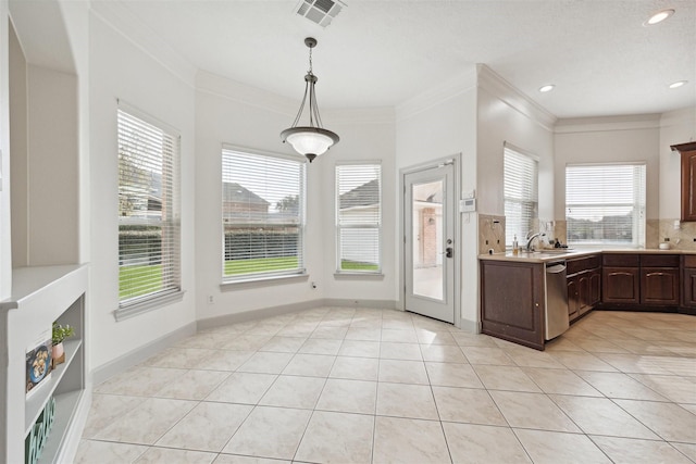 kitchen with dark brown cabinetry, pendant lighting, light tile patterned floors, and stainless steel dishwasher