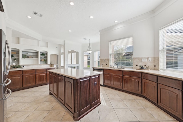 kitchen with built in shelves, sink, a center island, decorative light fixtures, and appliances with stainless steel finishes