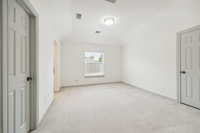 unfurnished bedroom with a textured ceiling, light colored carpet, and vaulted ceiling