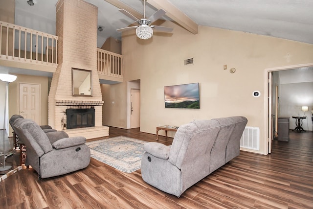 living room with ceiling fan, beamed ceiling, wood-type flooring, and a brick fireplace