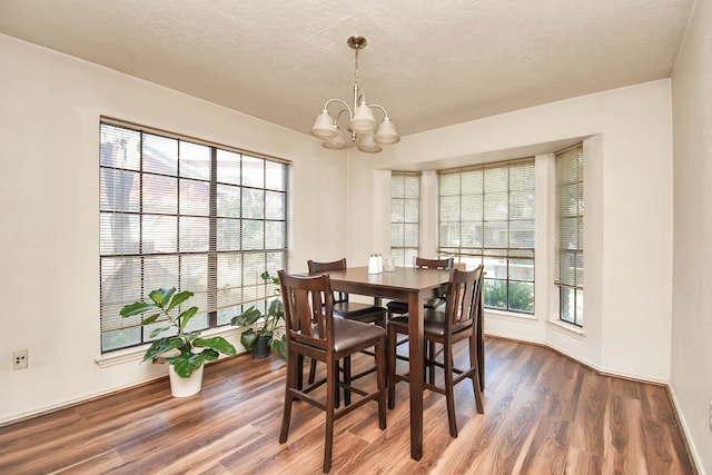 dining space with hardwood / wood-style floors, a textured ceiling, and a notable chandelier