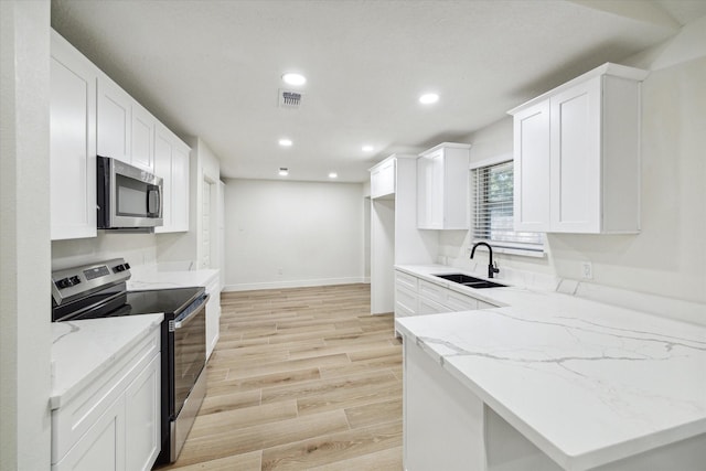 kitchen with sink, stainless steel appliances, light stone counters, light hardwood / wood-style flooring, and white cabinets