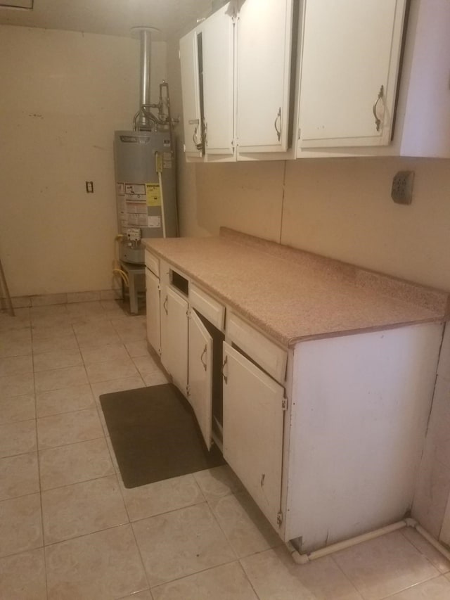 kitchen featuring white cabinets, light tile patterned floors, and gas water heater