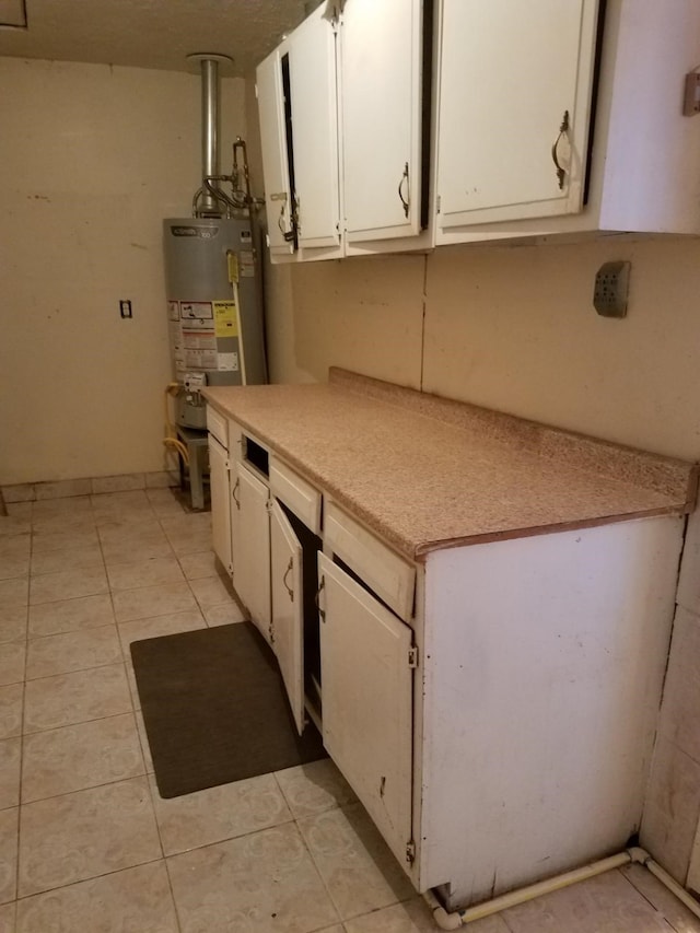 kitchen with white cabinetry, water heater, and light tile patterned flooring