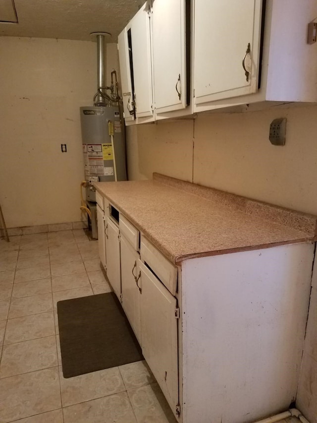 kitchen featuring white cabinetry, light tile patterned floors, and water heater