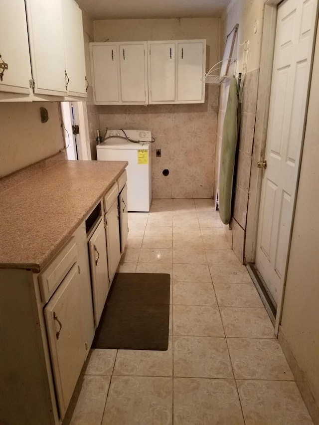 kitchen featuring white cabinets, light tile patterned floors, and washer / clothes dryer