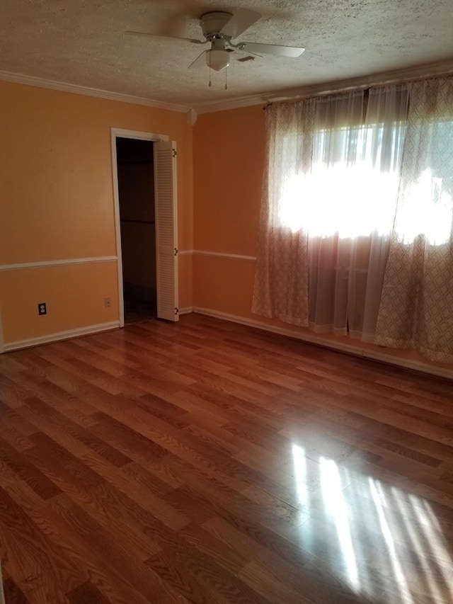 empty room with hardwood / wood-style floors, a textured ceiling, ceiling fan, and ornamental molding