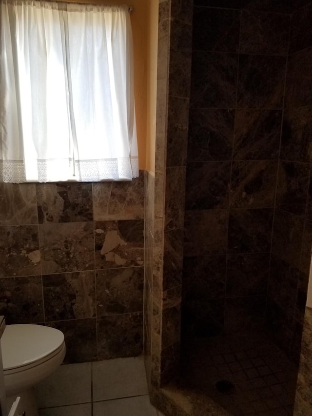 bathroom with tile patterned floors, walk in shower, tile walls, and toilet