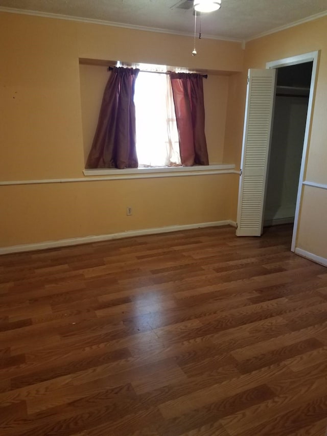 unfurnished bedroom with ceiling fan, crown molding, and dark wood-type flooring