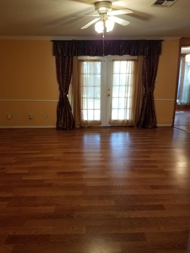 empty room with ceiling fan, french doors, dark wood-type flooring, a textured ceiling, and ornamental molding