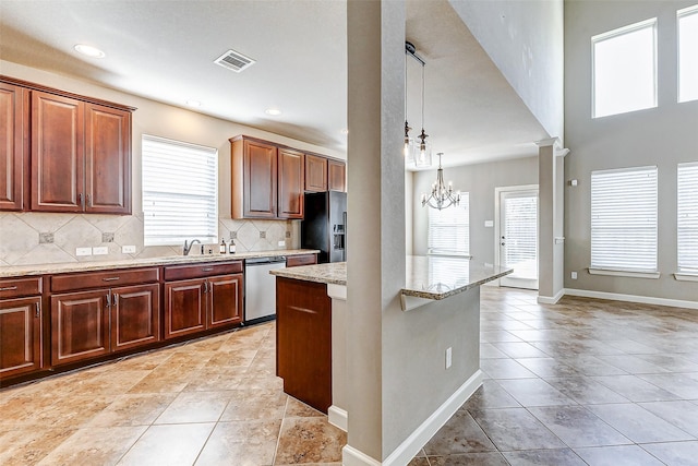 kitchen featuring black refrigerator with ice dispenser, light stone counters, stainless steel dishwasher, a notable chandelier, and decorative backsplash