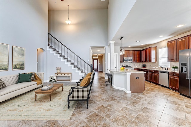 kitchen featuring a kitchen breakfast bar, light stone counters, stainless steel appliances, decorative light fixtures, and a kitchen island