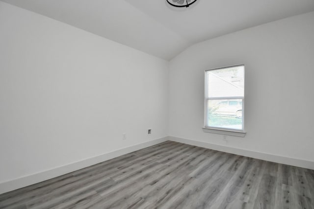 spare room featuring light hardwood / wood-style floors and vaulted ceiling