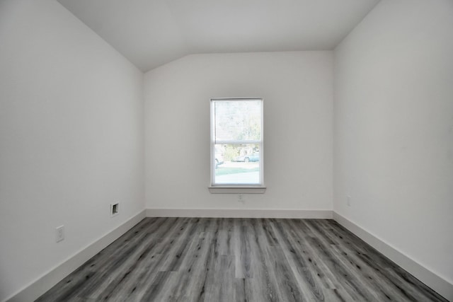 spare room with wood-type flooring and lofted ceiling