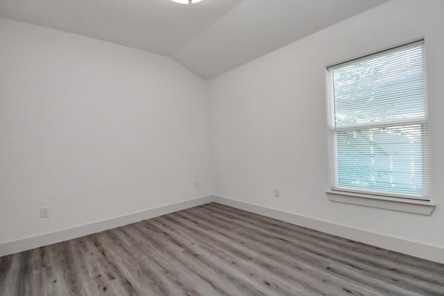 unfurnished room featuring hardwood / wood-style floors and vaulted ceiling