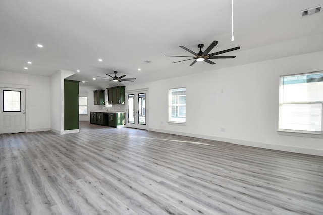 unfurnished living room featuring ceiling fan, plenty of natural light, and light wood-type flooring