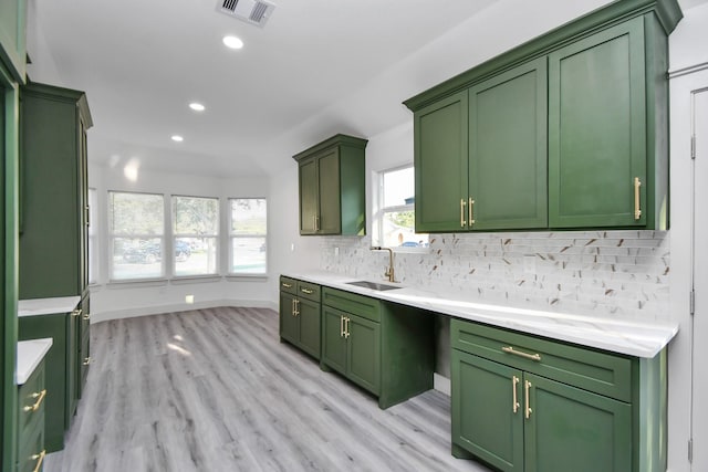 kitchen with tasteful backsplash, green cabinetry, light hardwood / wood-style floors, and sink