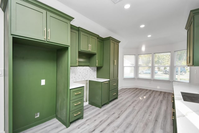 kitchen featuring green cabinets, light stone countertops, backsplash, and light hardwood / wood-style flooring