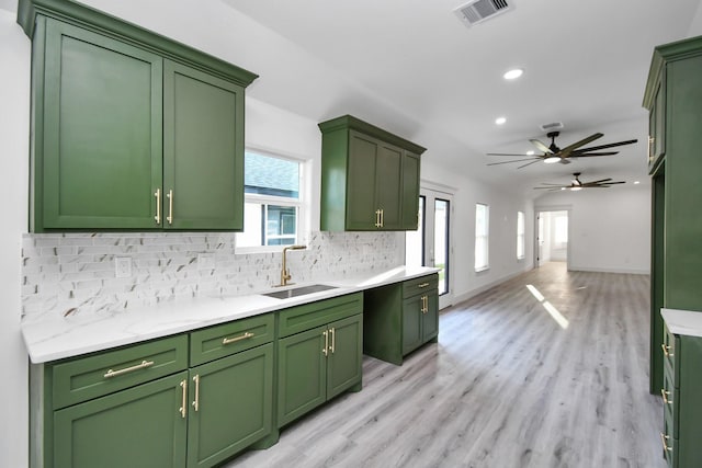 kitchen with green cabinets, a healthy amount of sunlight, sink, and tasteful backsplash