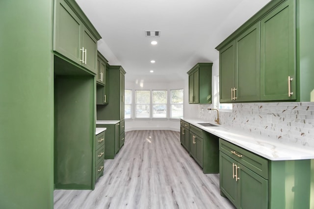 kitchen featuring green cabinets, decorative backsplash, sink, and light hardwood / wood-style floors