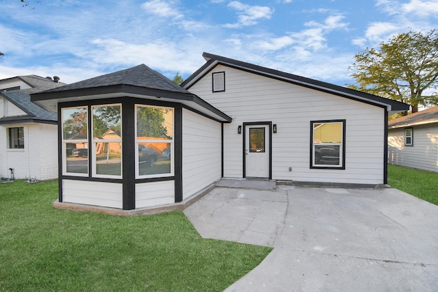 rear view of property featuring a patio and a lawn