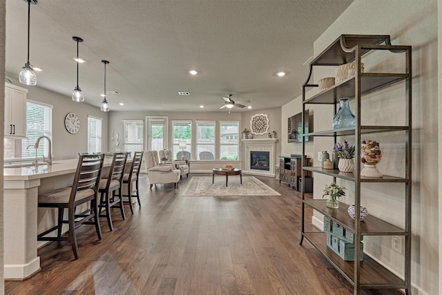 interior space with dark hardwood / wood-style flooring, a breakfast bar, sink, decorative light fixtures, and white cabinetry