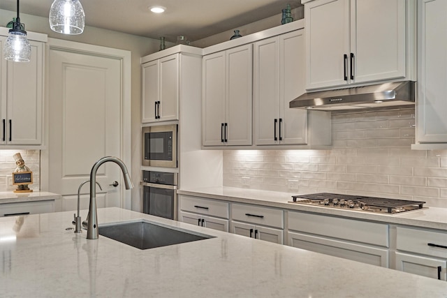 kitchen with decorative light fixtures, light stone counters, and stainless steel appliances