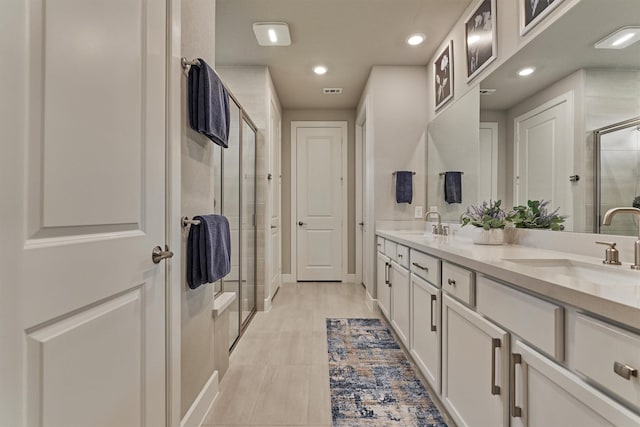 bathroom featuring a shower with door and vanity