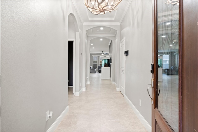 hallway featuring a tray ceiling, crown molding, and a chandelier