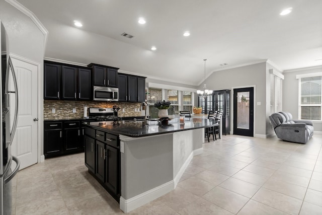 kitchen featuring stainless steel appliances, a kitchen island with sink, crown molding, dark stone countertops, and lofted ceiling