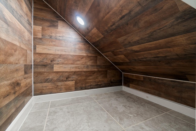 bonus room with tile patterned floors, wooden walls, and vaulted ceiling