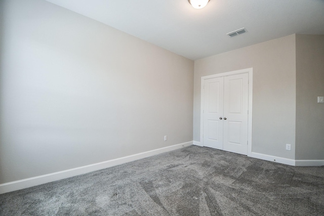 unfurnished bedroom featuring a closet and dark carpet